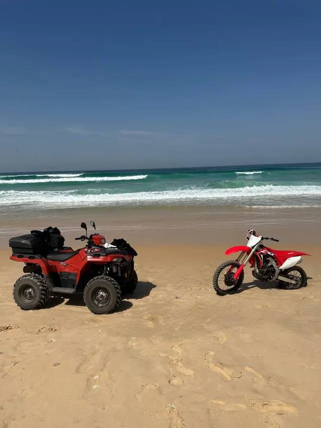Un quad rouge et une moto sur le sable face à l’Atlantique